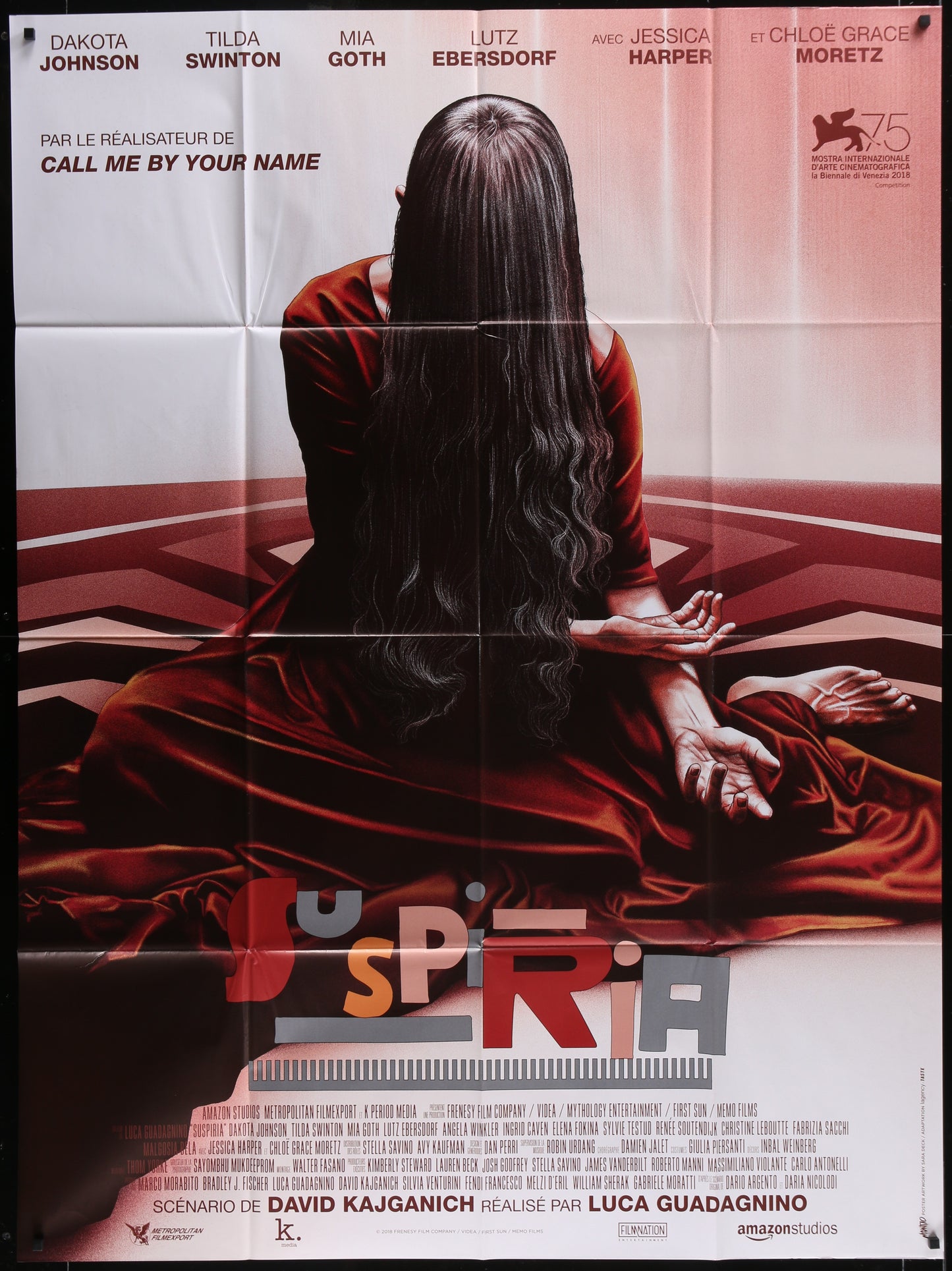 A movie poster for 'Suspiria' featuring a female figure in a red dress with a blurred background, indicating a horror genre.
