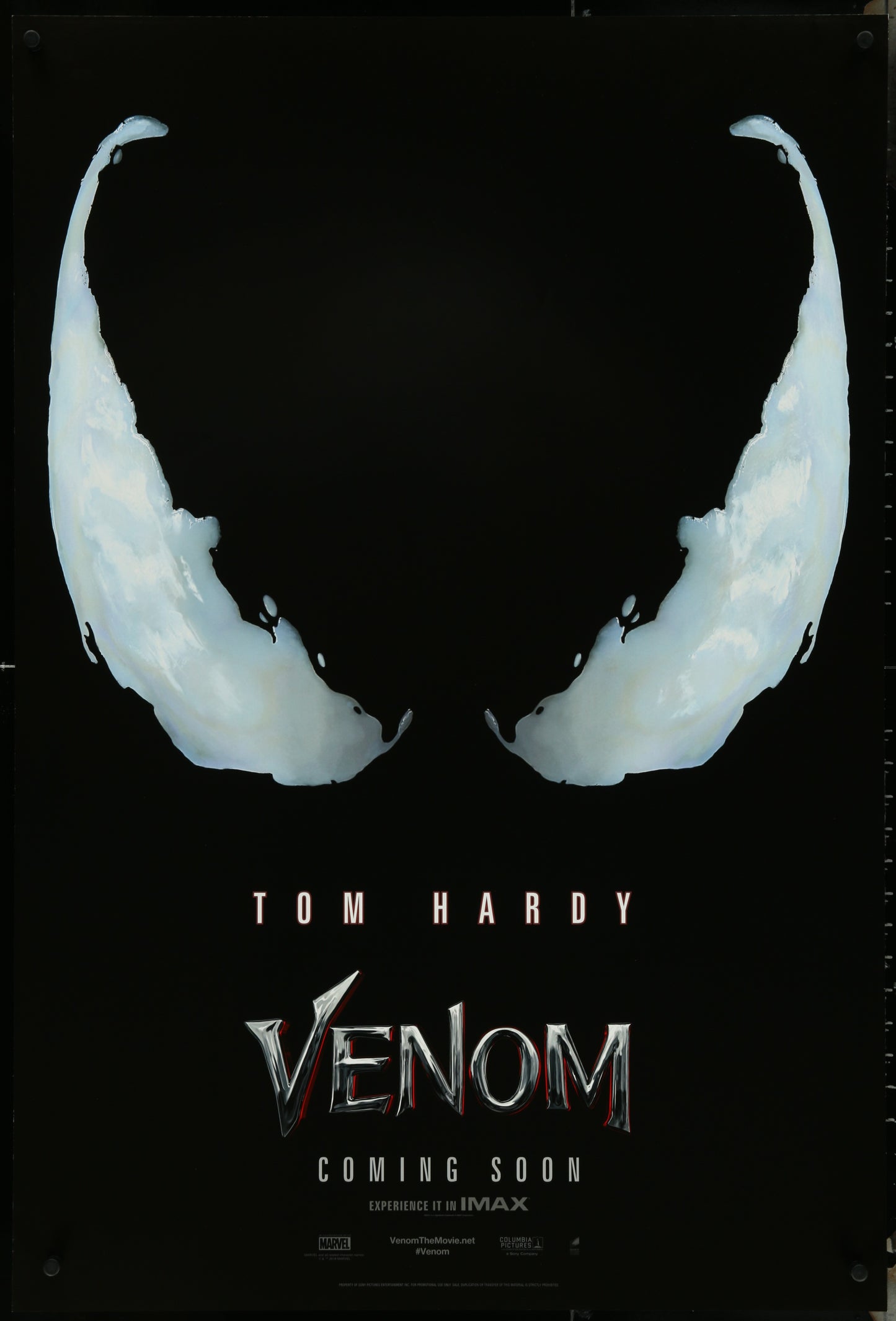 A promotional one-sheet movie poster for the film Venom, featuring the character's mask in the foreground with the title and 'Coming Soon' text in the background.