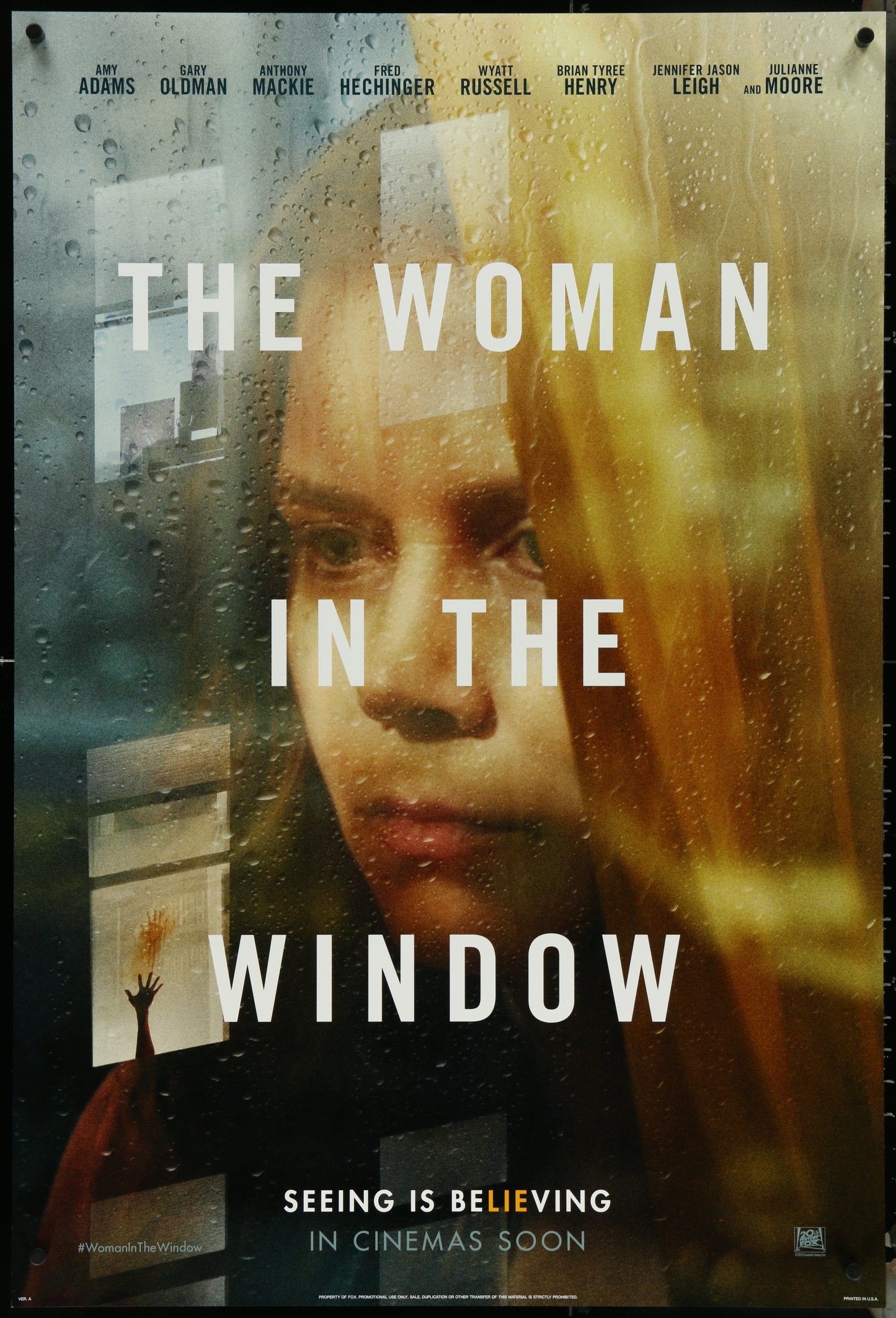 A movie poster for 'The Woman In The Window' featuring a woman's face peeking out from behind a window, with a rainy background.