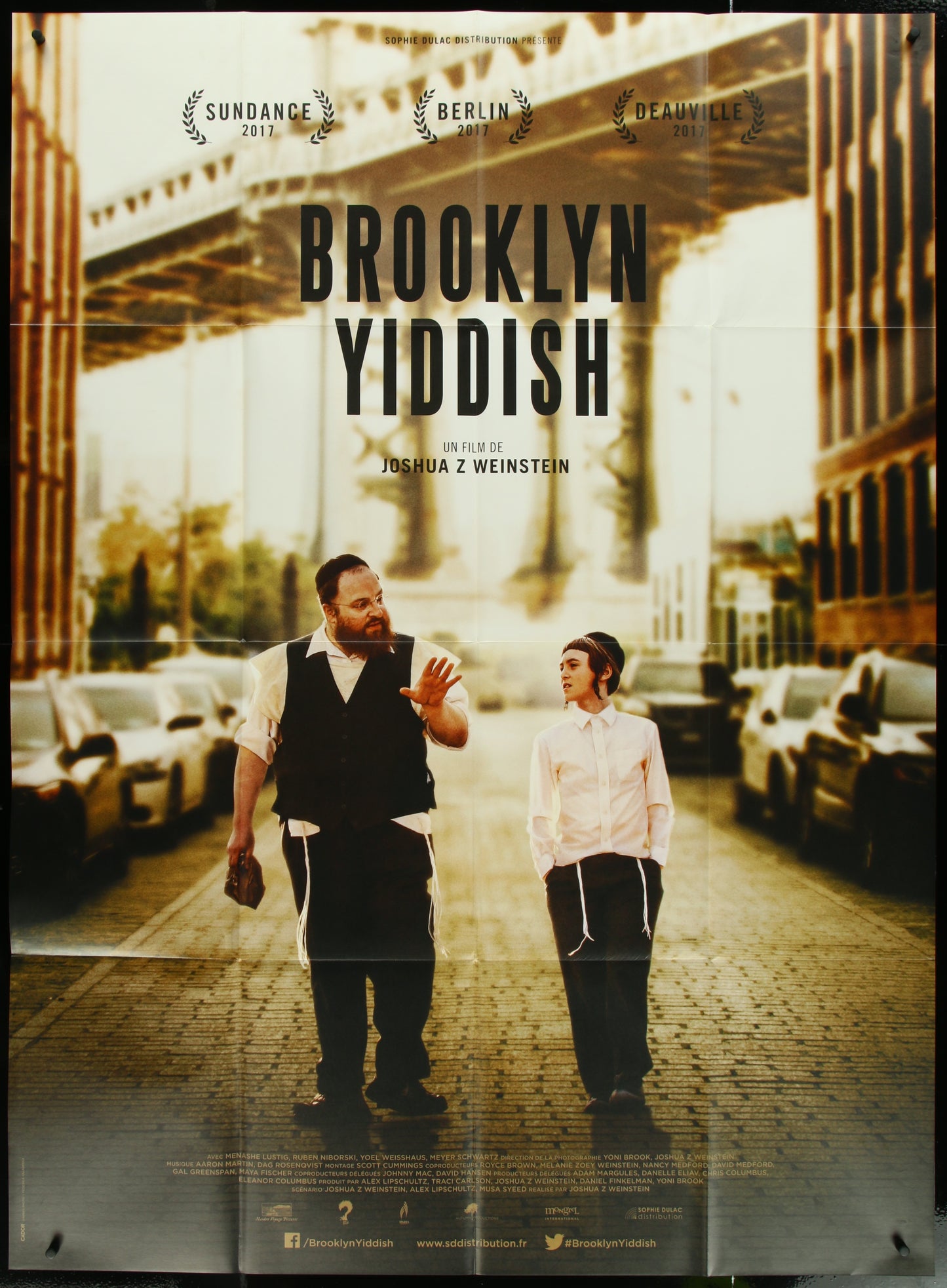 A movie poster for 'Brooklyn Yiddish' featuring two men conversing on a street corner with a bridge and cars in the background. The poster is in a vintage style and has French text along with English text.