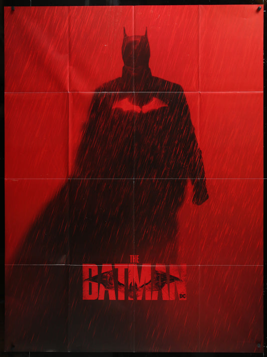 Dark silhouette of a superhero in a cape against a red background with 'The Batman' logo.
