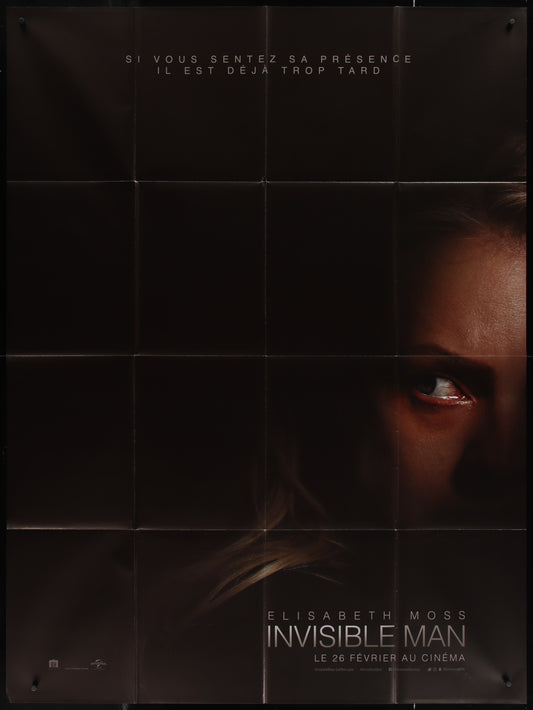 A poster of the movie 'The Invisible Man' featuring a close-up image of an actress, likely Elisabeth Moss, with a dramatic expression. The poster is predominantly black with white and red text.