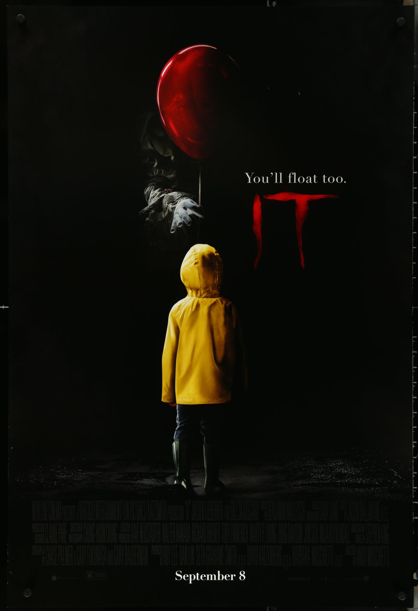 Original US one-sheet movie poster for It (2017) featuring a young boy in a yellow raincoat with a large red balloon, and a menacing clown figure in the background.