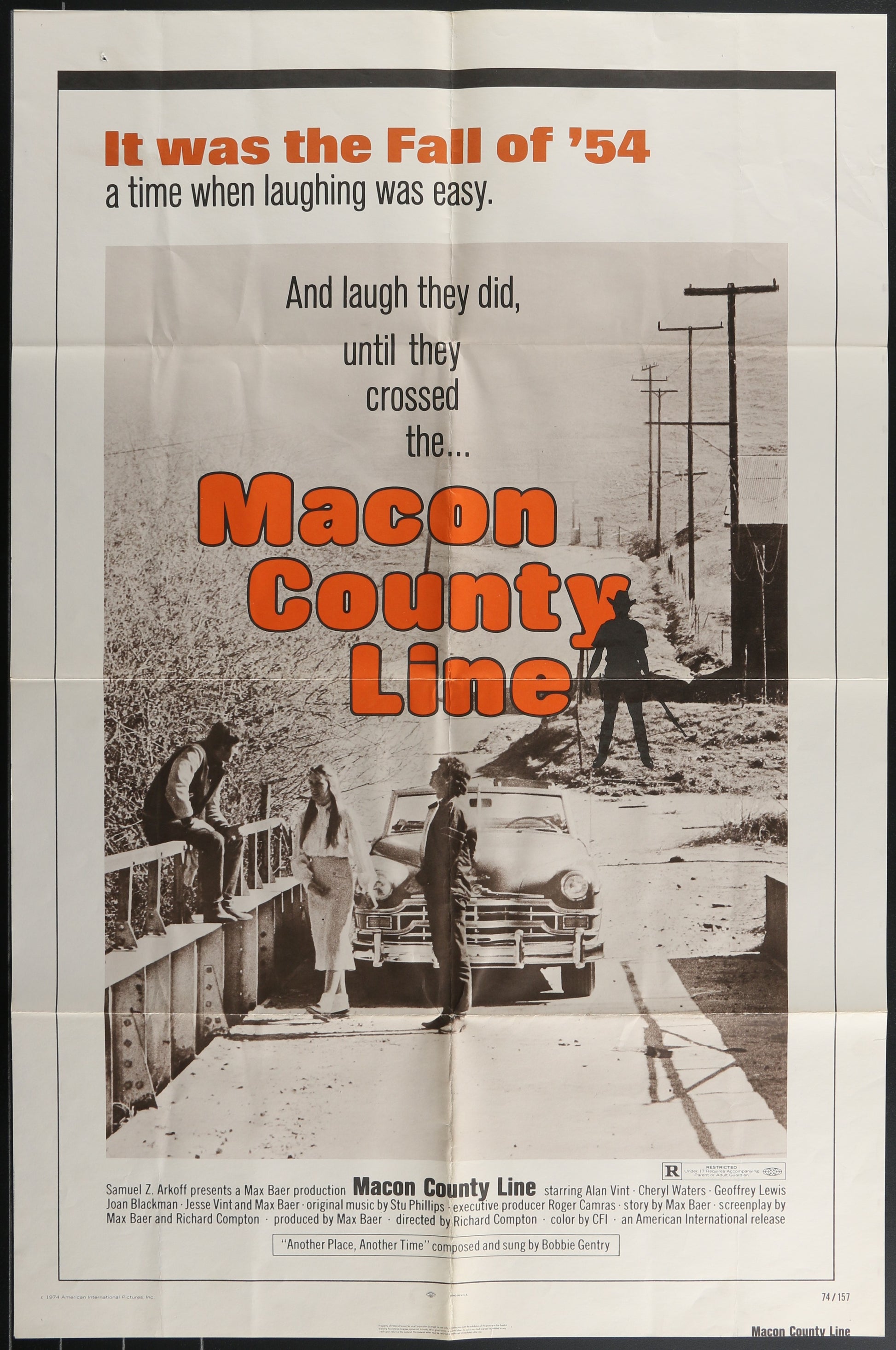 Movie poster for 'Macon County Line' with text and black and white image of people by a fence.