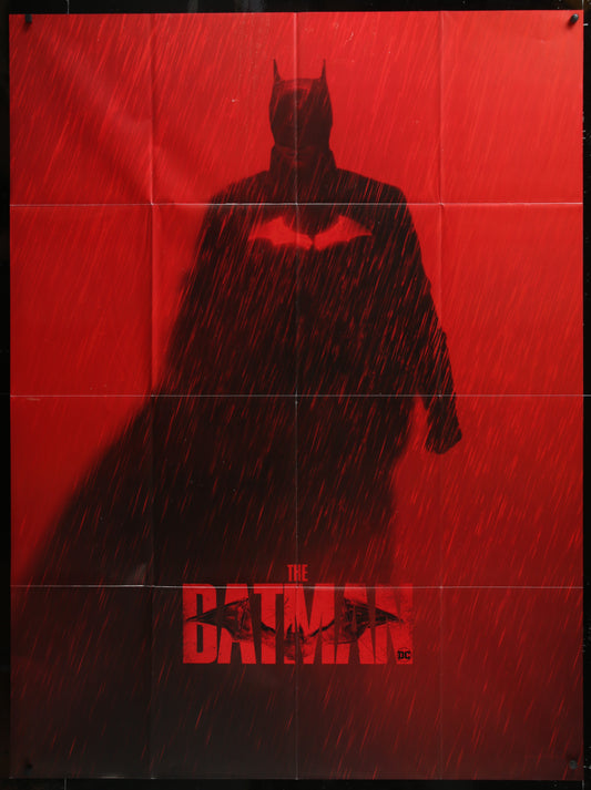Dark silhouette of a superhero in a cape against a red background with 'The Batman' logo.