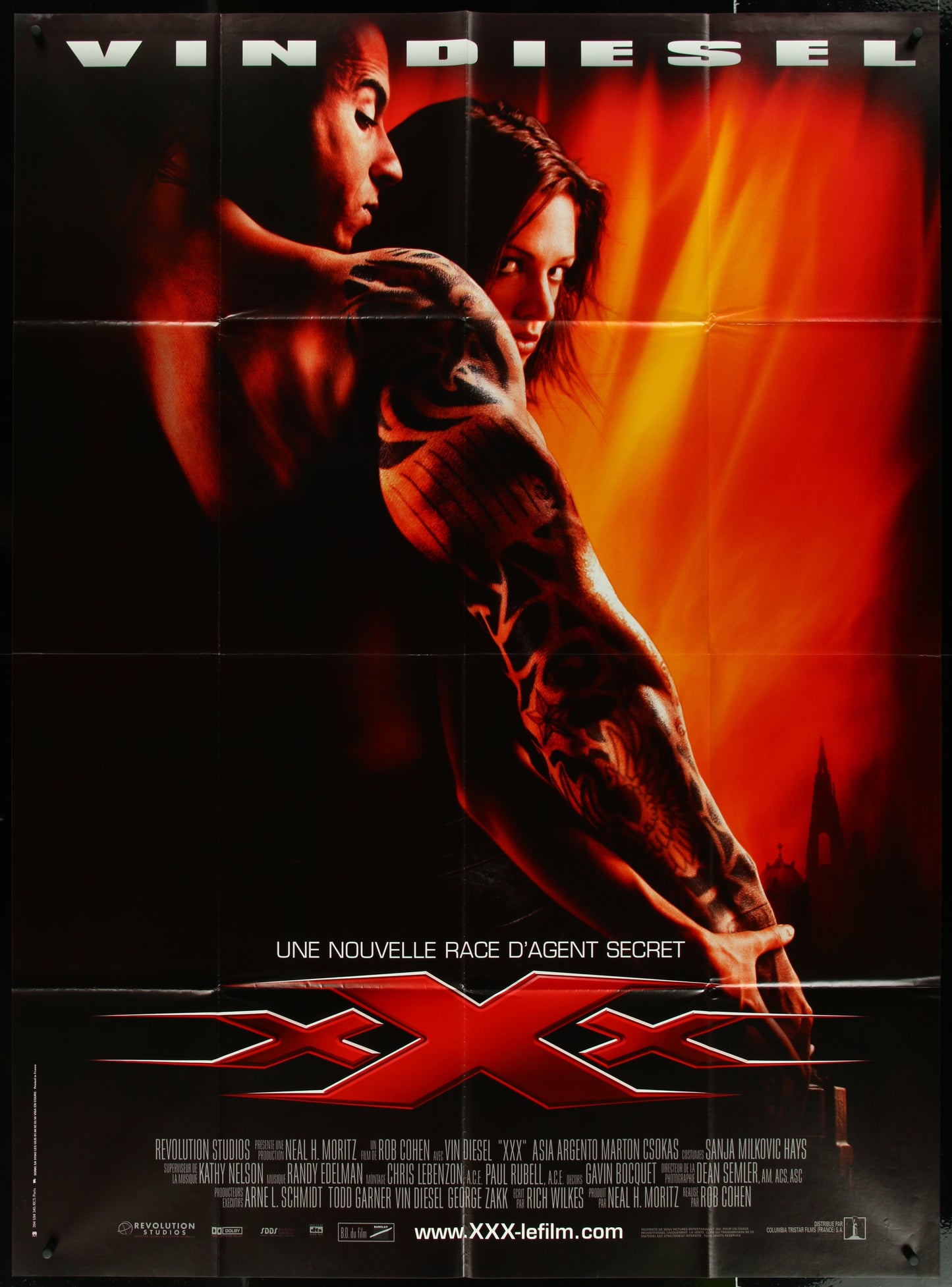 A vintage movie poster featuring Vin Diesel and Asia Argento in the film XXX, with a red and orange backdrop.